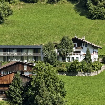 Alpine Stays for all Generations by Family Rainer Mehrere Häuser auf einem grünen Hügel mit vielen Bäumen