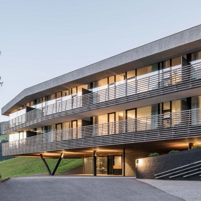 Alpine Stays for all Generations by Family Rainer Modernes Gebäude mit beleuchteten Fenstern in grüner Hügellandschaft