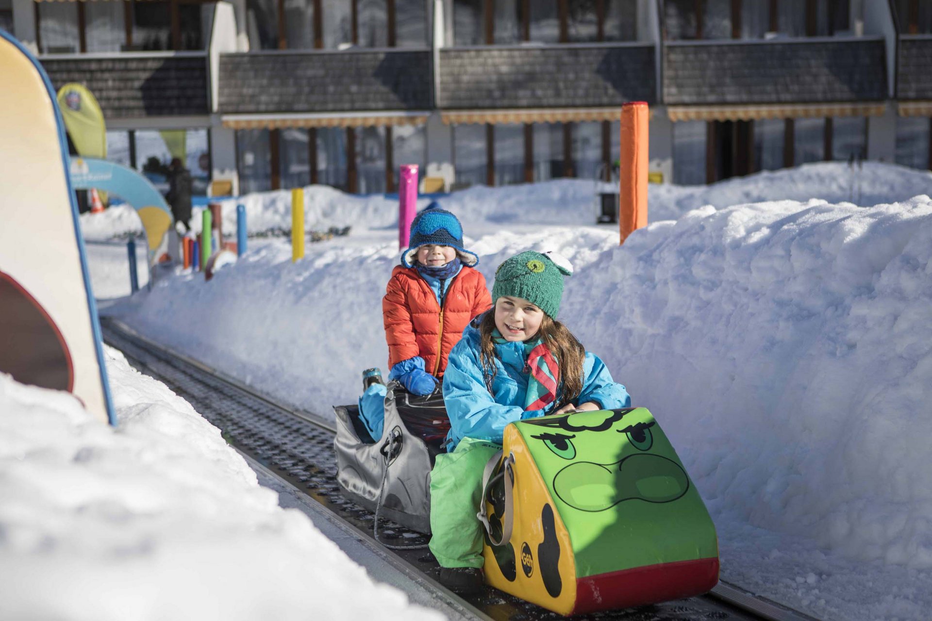 Experience exciting adventures with Raini! Children riding a small train on tracks through a snowy landscape