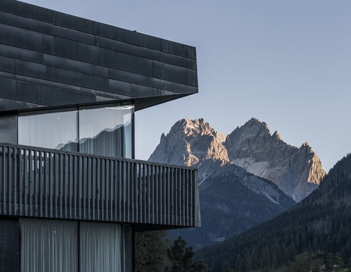 1 Familienhotel in Südtirol und 3 Residences: Family Resort Rainer Modernes Gebäude in grüner Hügellandschaft bei sonnigem Himmel