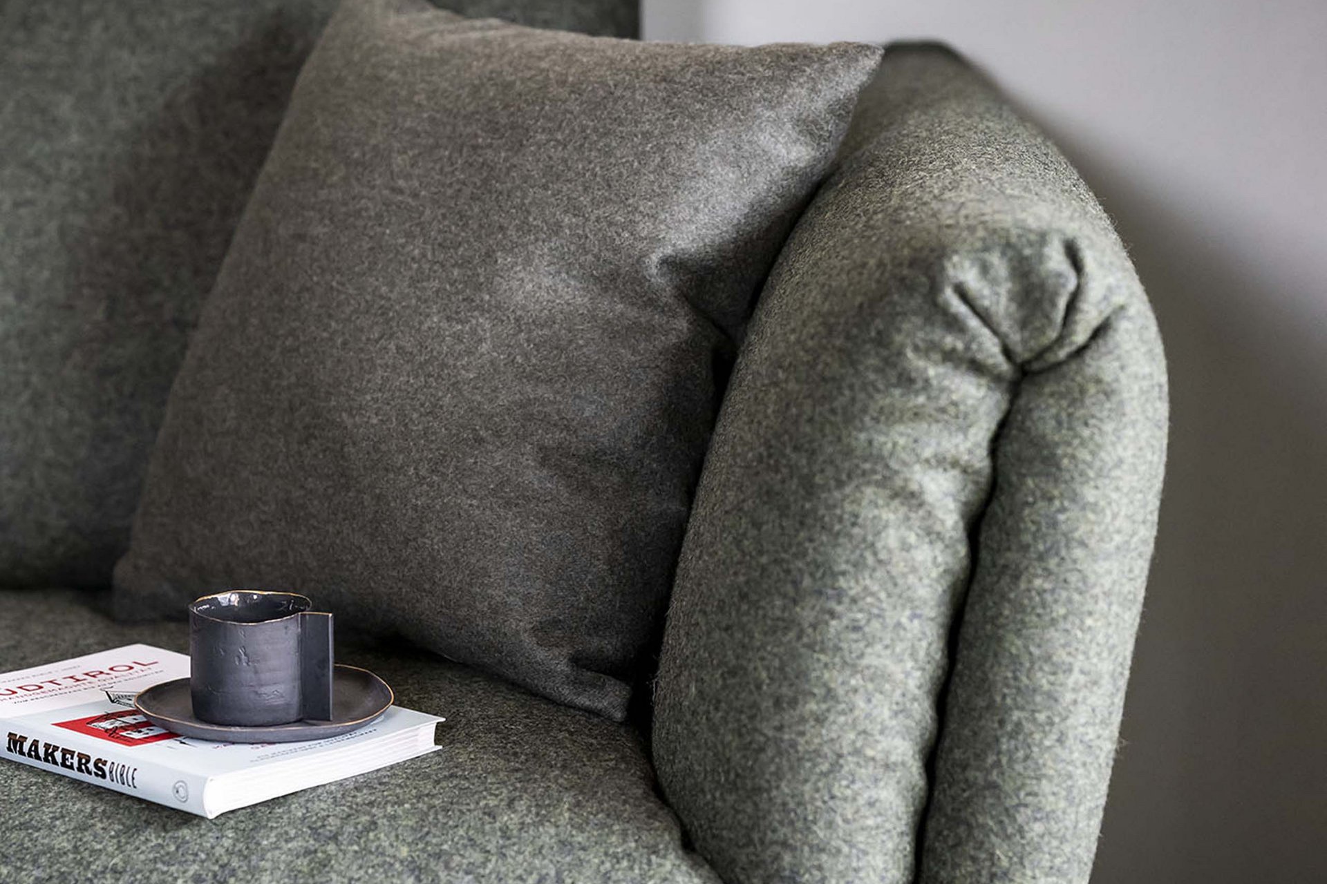 Stylish holidays at the Residence Paramount Alma Gray fabric sofa with pillow and book topped with cup on the armrest