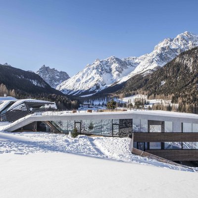 Alpine Stays for all Generations by Family Rainer Modernes Haus im Schnee mit Blick auf schneebedeckte Berge und Wald