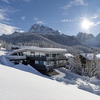 1 Familienhotel in Südtirol und 3 Residences: Family Resort Rainer Modernes Haus im Schnee mit Blick auf schneebedeckte Berge und Wald