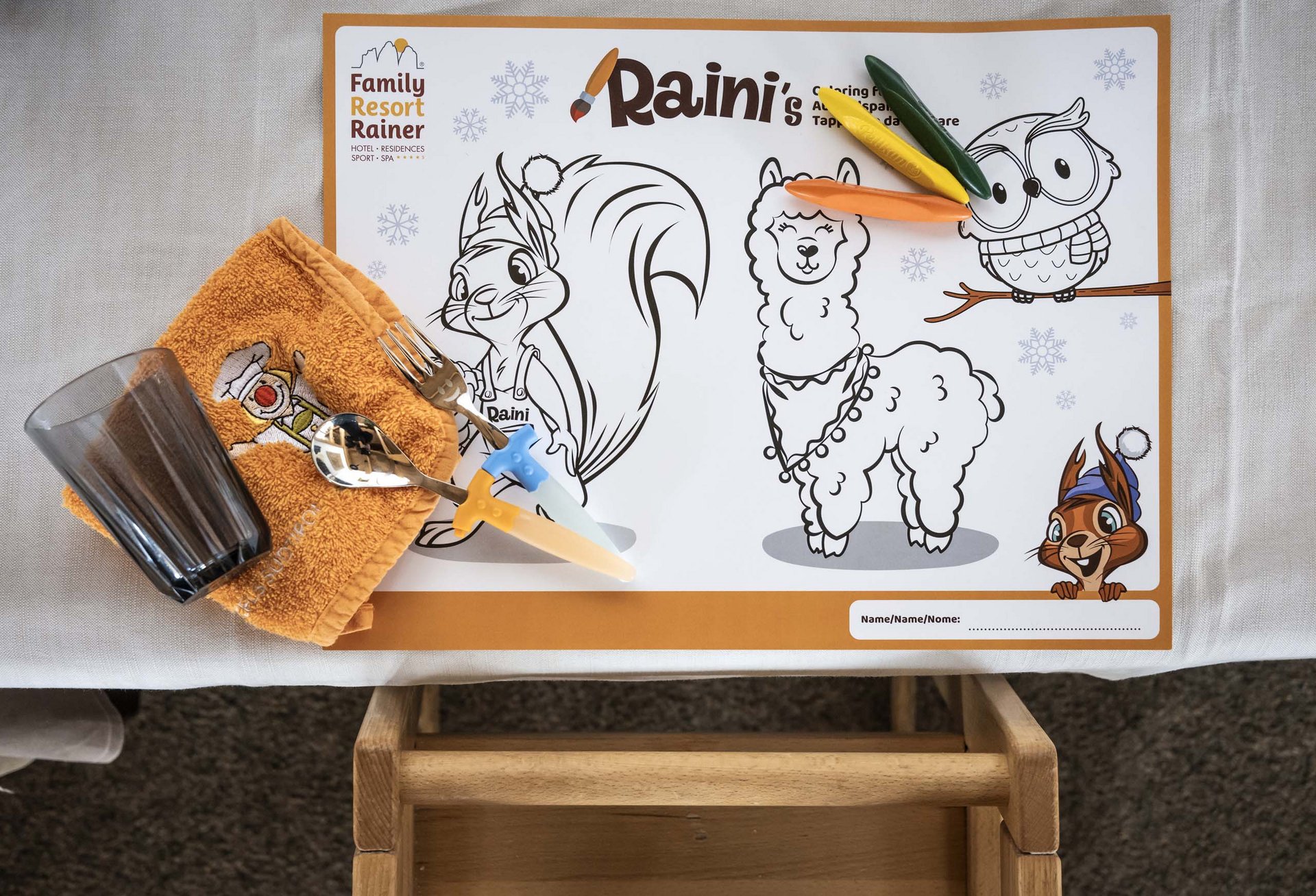 The children’s buffet at the Familienhotel Rainer Kids table set with coloring placemat, cutlery, and glass at Family Resort Rainer