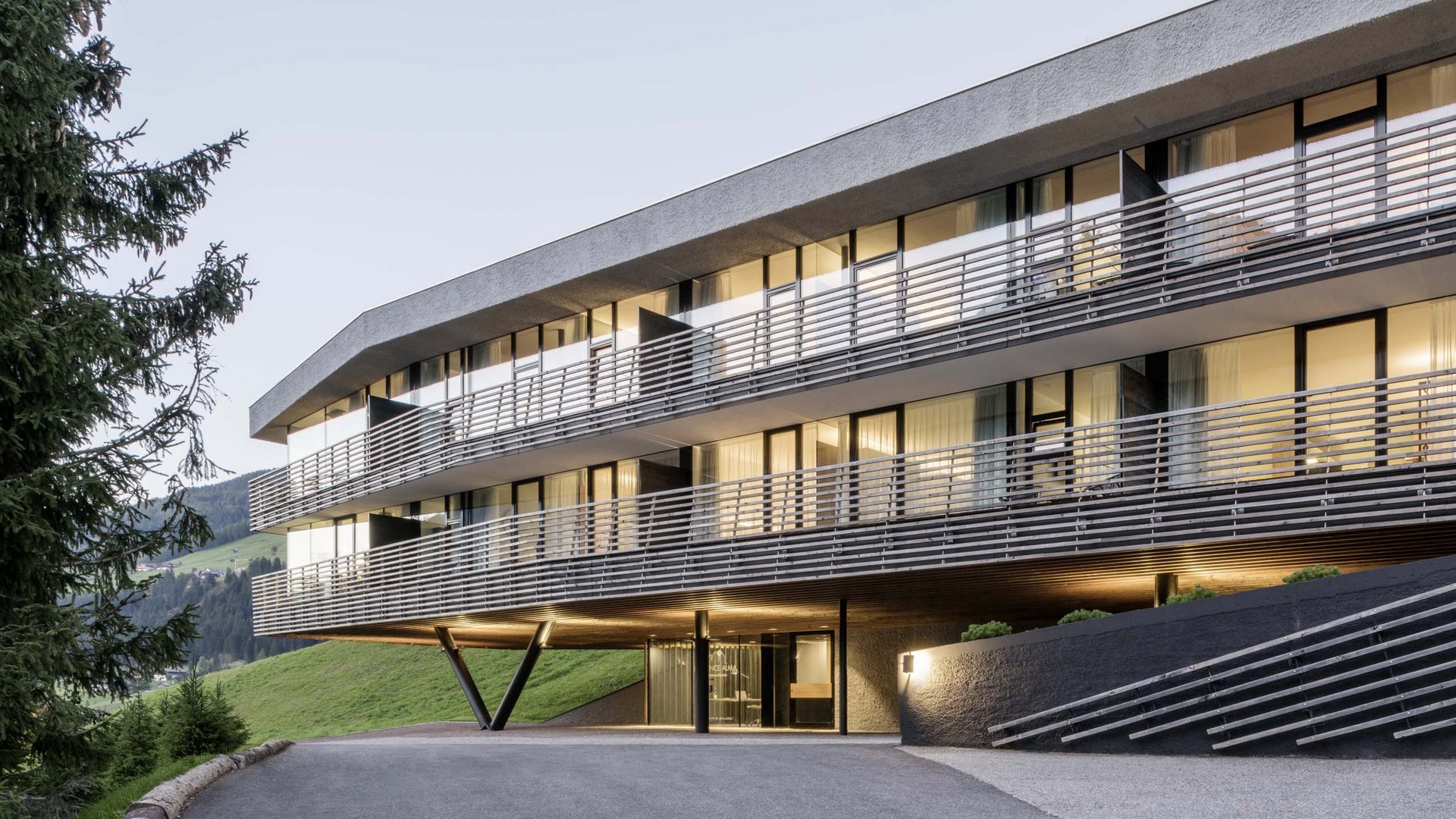 Stylish holidays at the Residence Paramount Alma Modern hotel building in mountains with lit windows at dusk