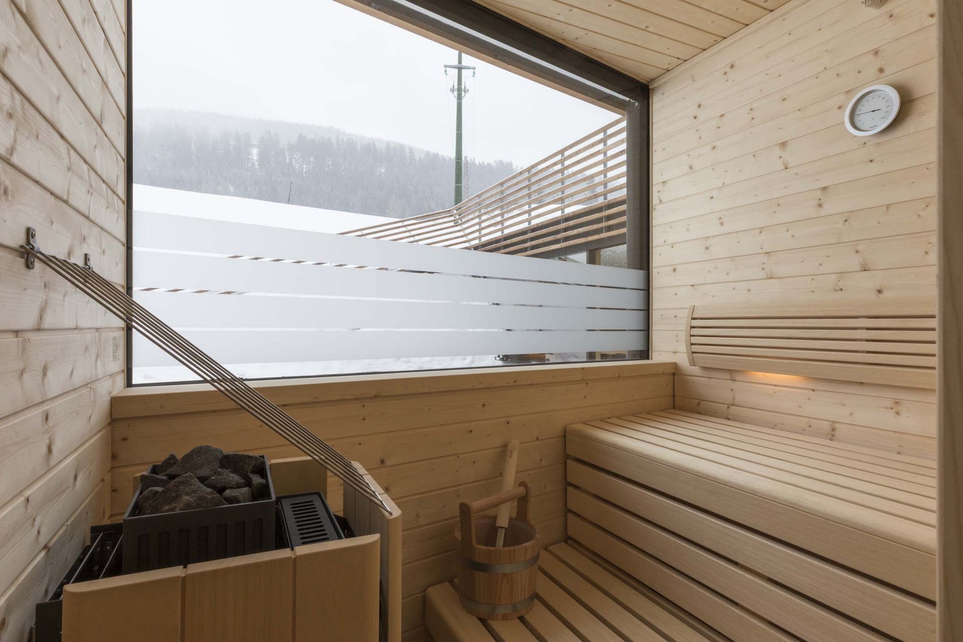 Stylish holidays at the Residence Paramount Alma Sauna with wooden interior and window view of snowy mountains