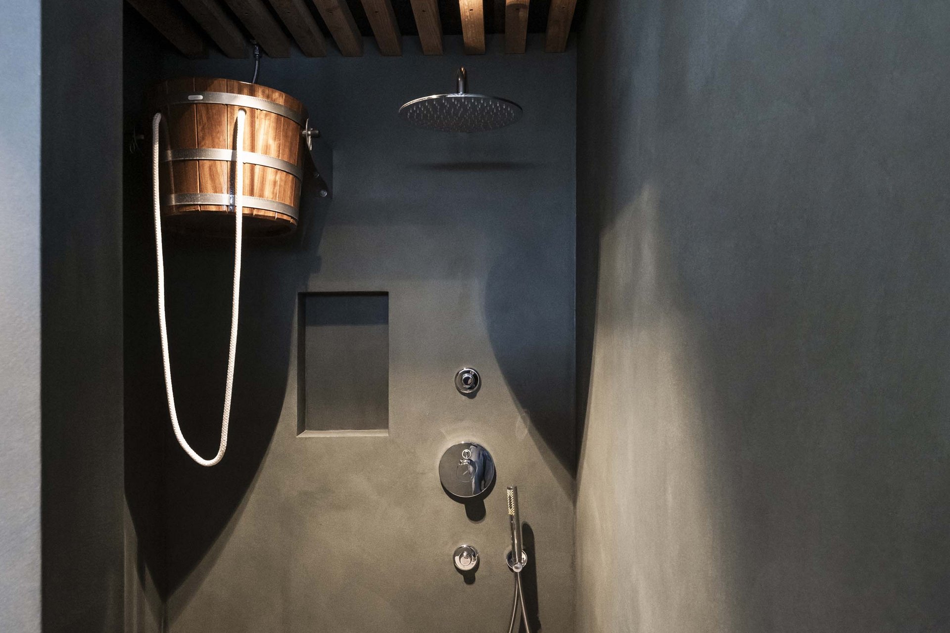 The Residence Königswarte Strata Modern shower with wooden bucket and rain showerhead in dark room