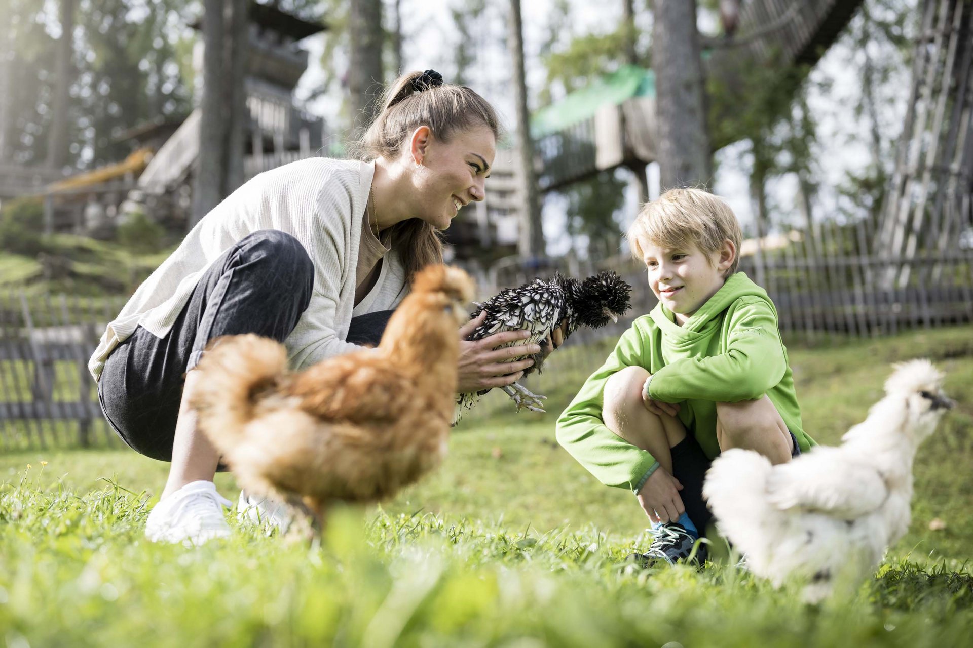 Experience exciting adventures with Raini! Woman and boy watching chickens playing in the garden