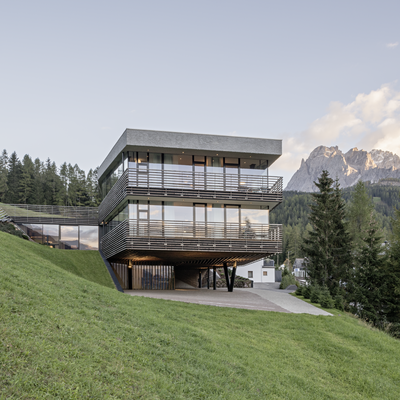 1 Familienhotel in Südtirol und 3 Residences: Family Resort Rainer Modernes Hotelgebäude bei Dämmerung in bergiger Landschaft