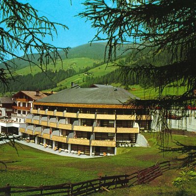 Alpine Stays for all Generations by Family Rainer Hotelgebäude in einem grünen Bergtal, umgeben von Tannenbäumen