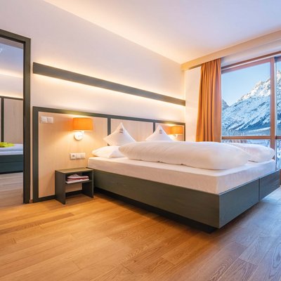 Alpine Stays for all Generations by Family Rainer Modernes Hotelzimmer mit Bergblick durch große Fenster