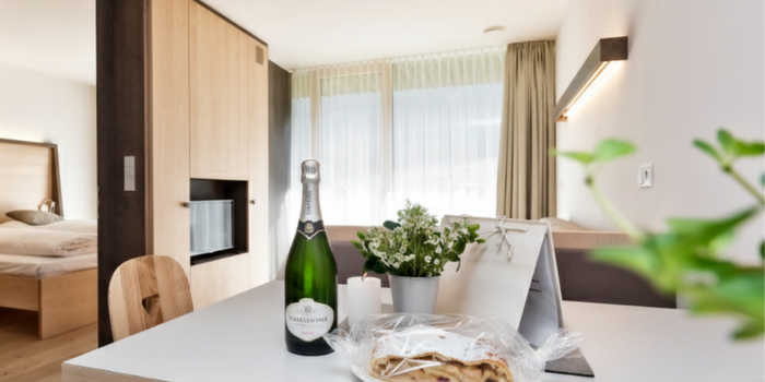 Your family resort in the Dolomites Modern living area with table, bottle of sparkling wine, cake and flowers