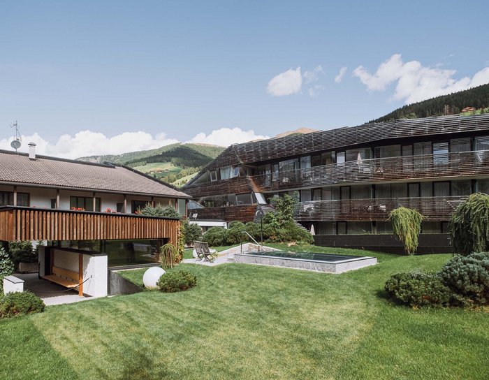 Alpine Stays for all Generations by Family Rainer Moderne Gebäude mit Garten und Bergen im Hintergrund an einem sonnigen Tag