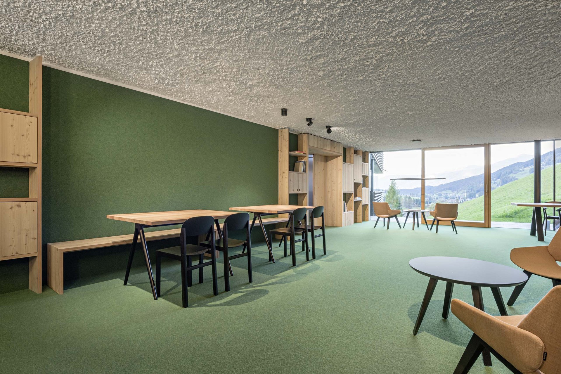 Stylish holidays at the Residence Paramount Alma Modern lounge with green walls, wooden furniture, and large glass window with mountain view