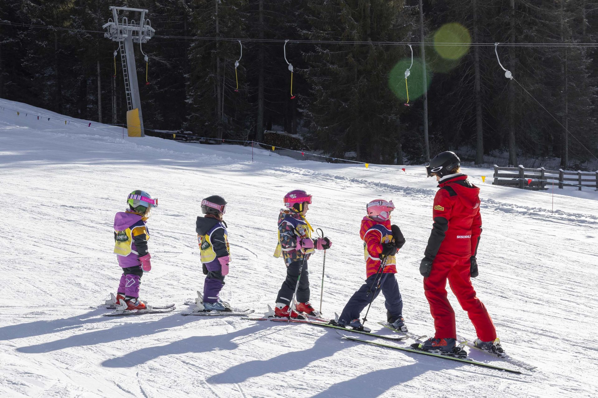 Experience exciting adventures with Raini! Ski instructor teaching four children lined up on a snowy slope