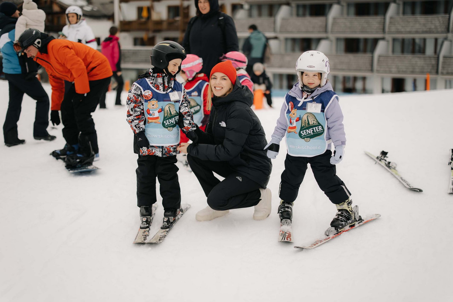 Your family resort in the Dolomites Children learning to ski with an instructor on a snowy slope