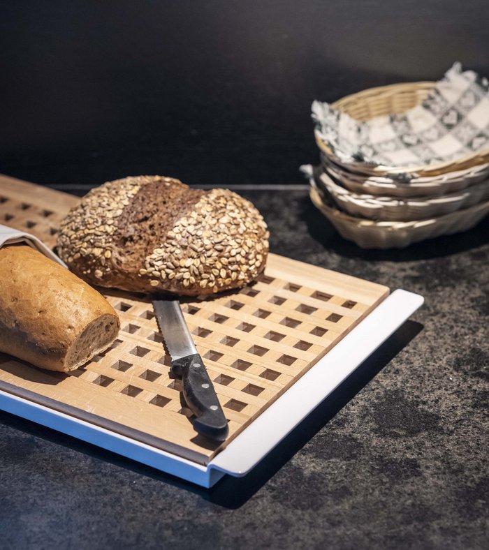 Family holidays at a gluten-free hotel Cut bread and knife on wooden cutting board in kitchen
