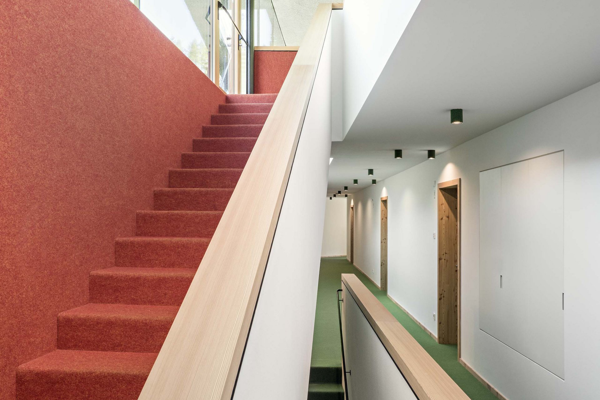 Stylish holidays at the Residence Paramount Alma Modern hallway with red and green carpeted stairs and wooden doors