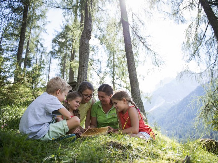 L’hotel con assistenza ai bambini in Alto Adige Bambini e donna che studiano insieme in una foresta con vista sulle montagne