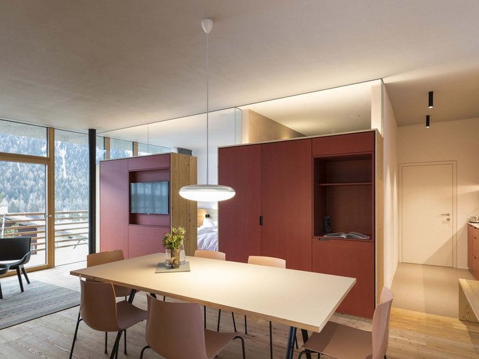 Stylish holidays at the Residence Paramount Alma Modern dining area with light chairs, table, and red cabinet near window and balcony