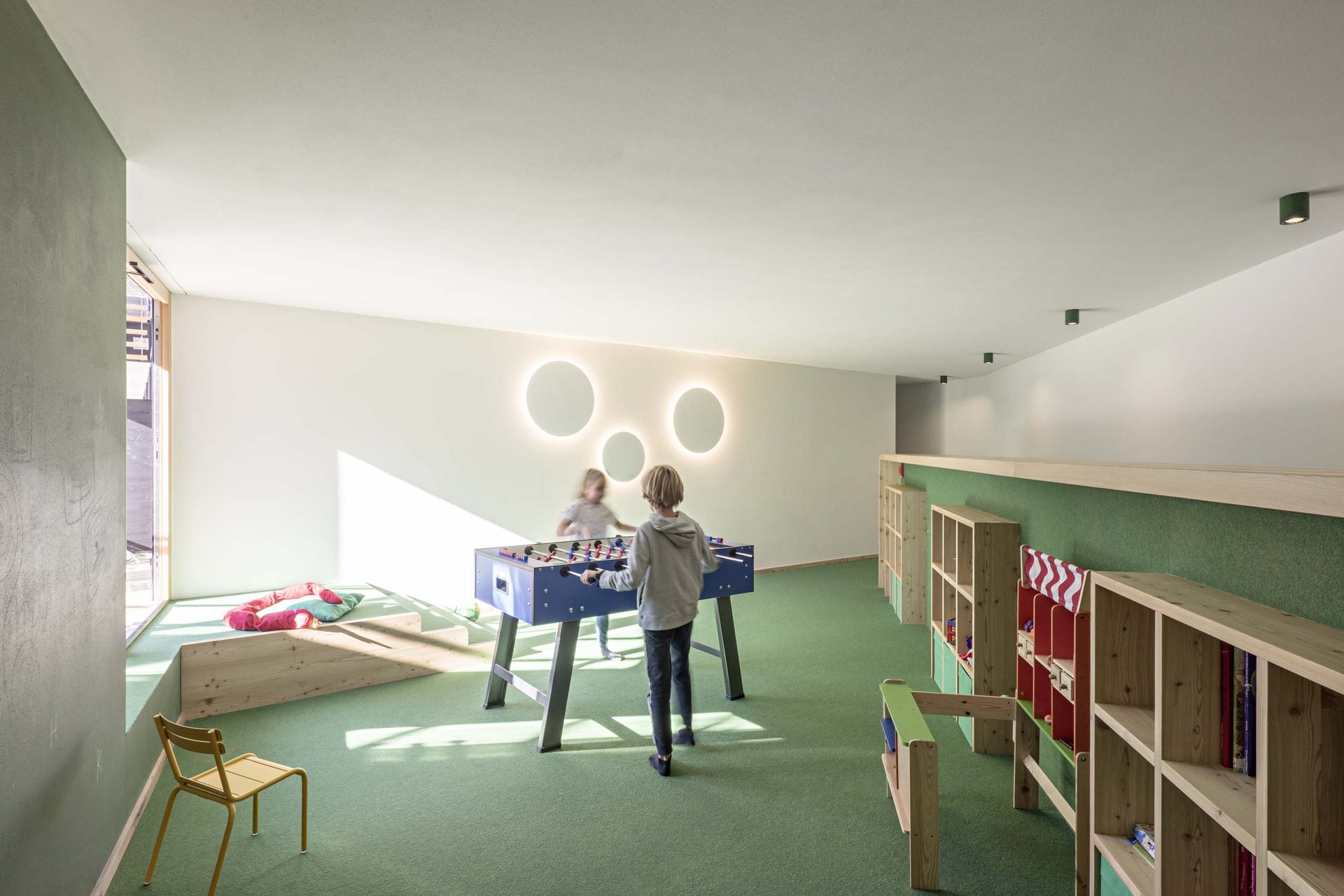 Stylish holidays at the Residence Paramount Alma Children playing foosball in a bright, modern playroom with green carpet