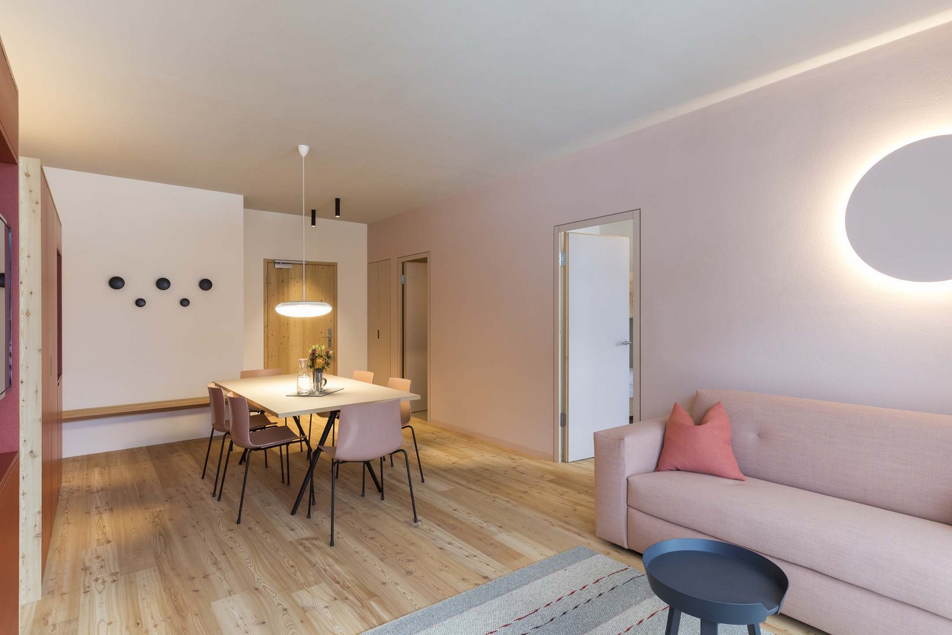 Stylish holidays at the Residence Paramount Alma Modern living room with dining table, pink sofa, and round wall lamp