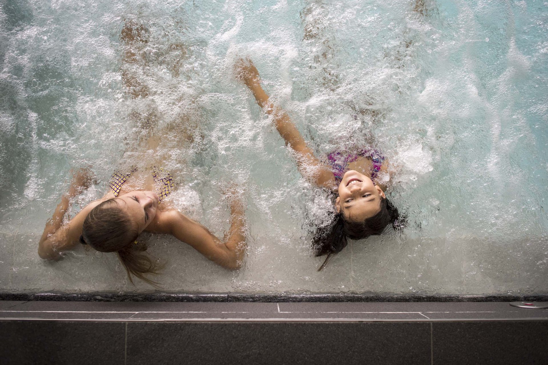 Your family resort in the Dolomites Two girls smiling and relaxing in a bubbling whirlpool pool