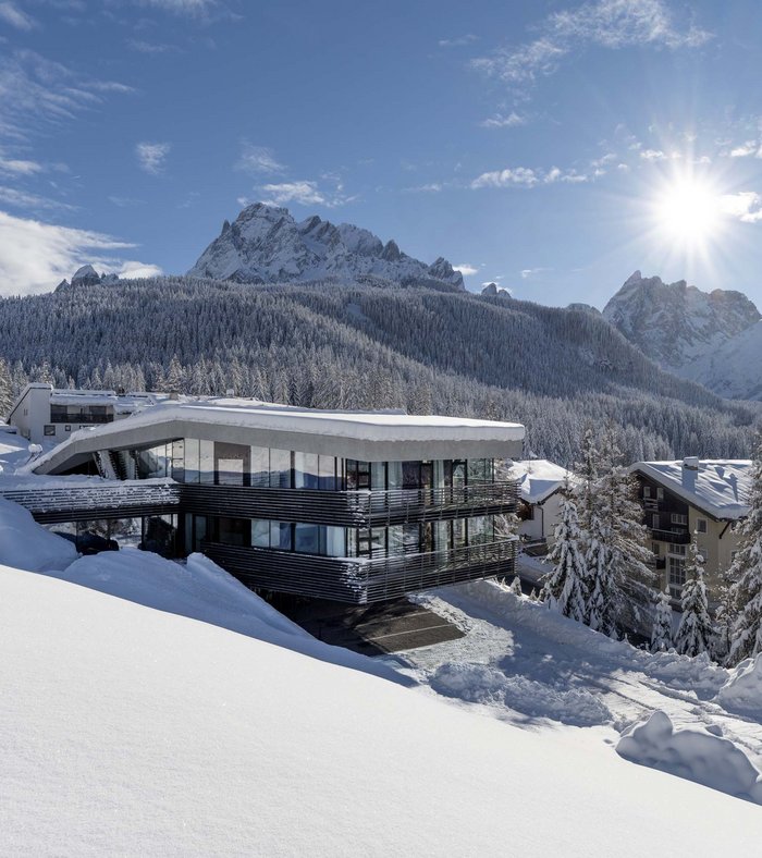 1 Familienhotel in Südtirol und 3 Residences: Family Resort Rainer Modernes Hotel im Schnee vor verschneiten Bergen und klarem Himmel