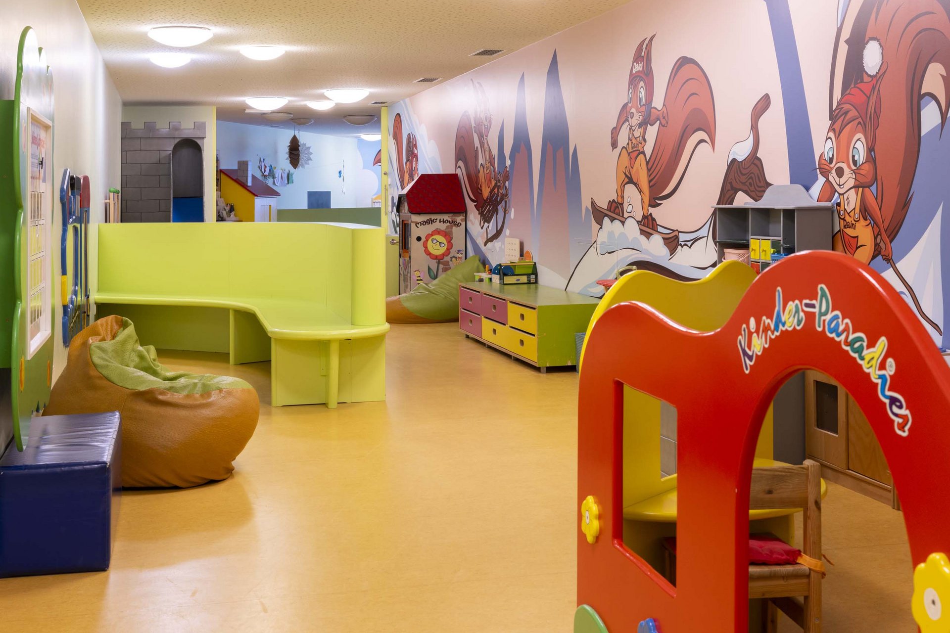 Experience exciting adventures with Raini! Colorful children's playroom with bean bags, toys, and wall murals