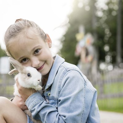 Alpine Stays for all Generations by Family Rainer Mädchen umarmt Kaninchen im Freien in einem Park