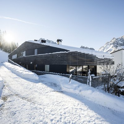 1 Familienhotel in Südtirol und 3 Residences: Family Resort Rainer Modernes Gebäude in verschneiter Berglandschaft mit klarem Himmel