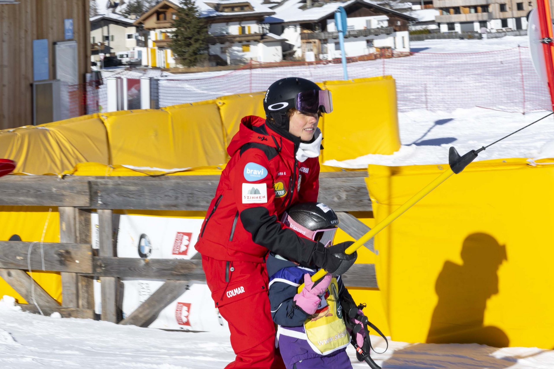 Experience exciting adventures with Raini! Ski instructor helping young child ski on snowy slope