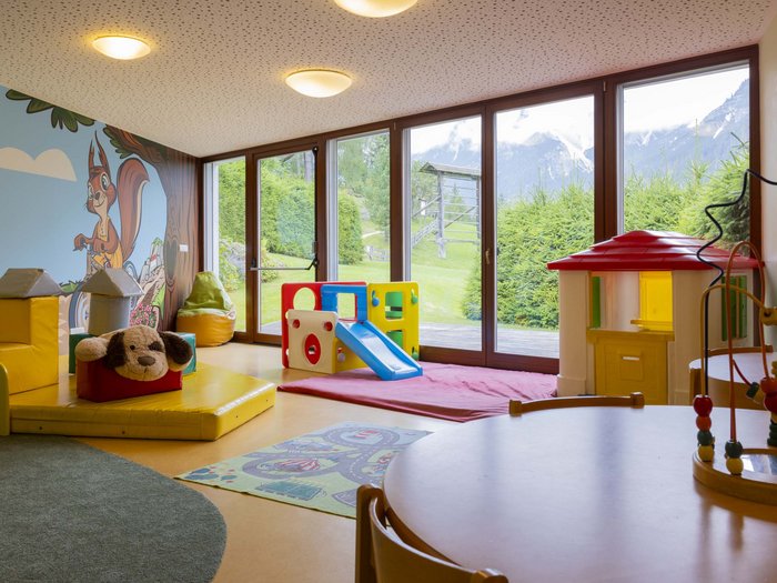 Experience exciting adventures with Raini! Children's playroom with playhouse, slide, and large windows showing mountain view